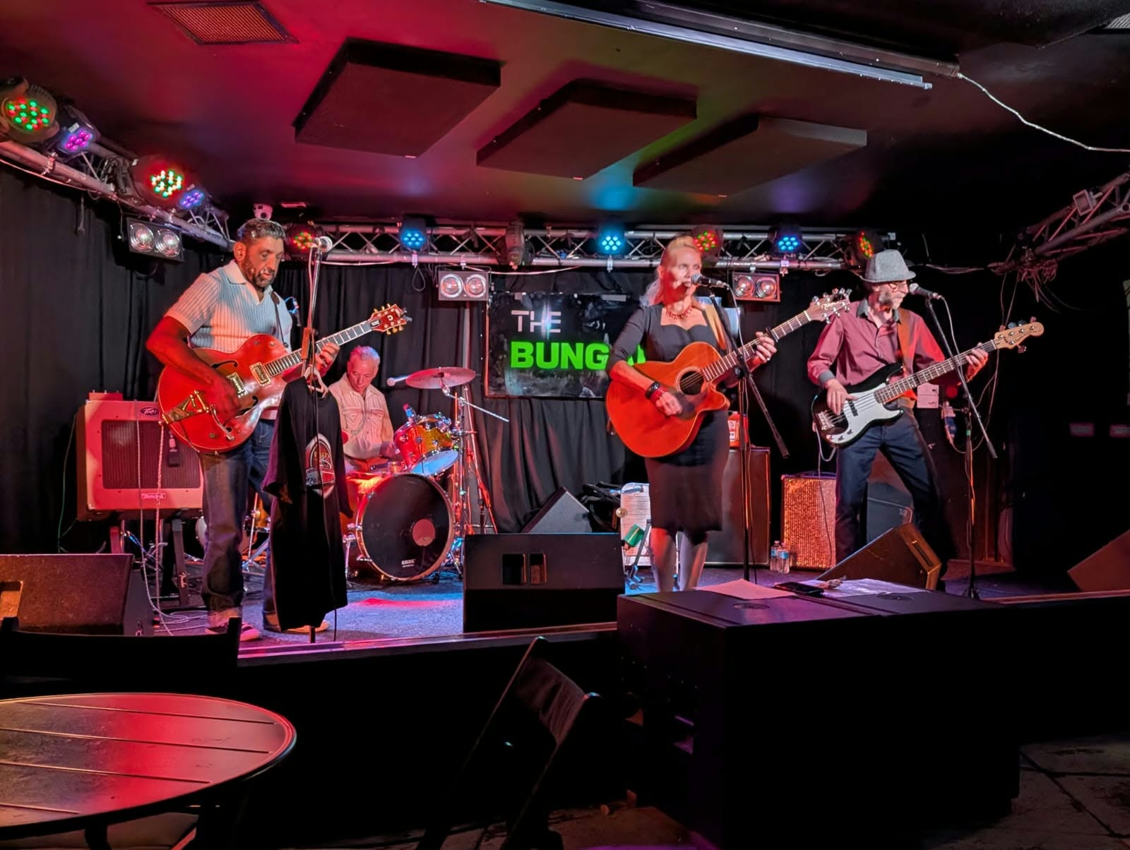 The band performing together on a stage lit in red and purple